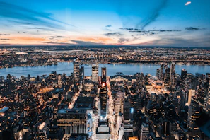 Aerial drone shot of a vibrant cityscape at sunset with glowing lights.