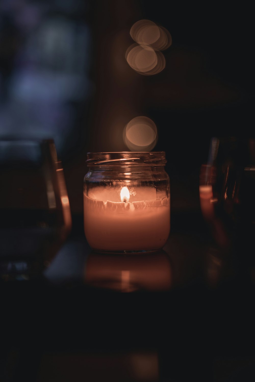 lighted candle in clear glass jar