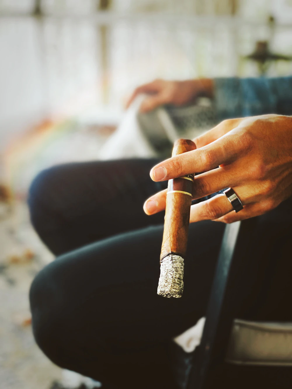 A hand holding a premium lit cigar in low light