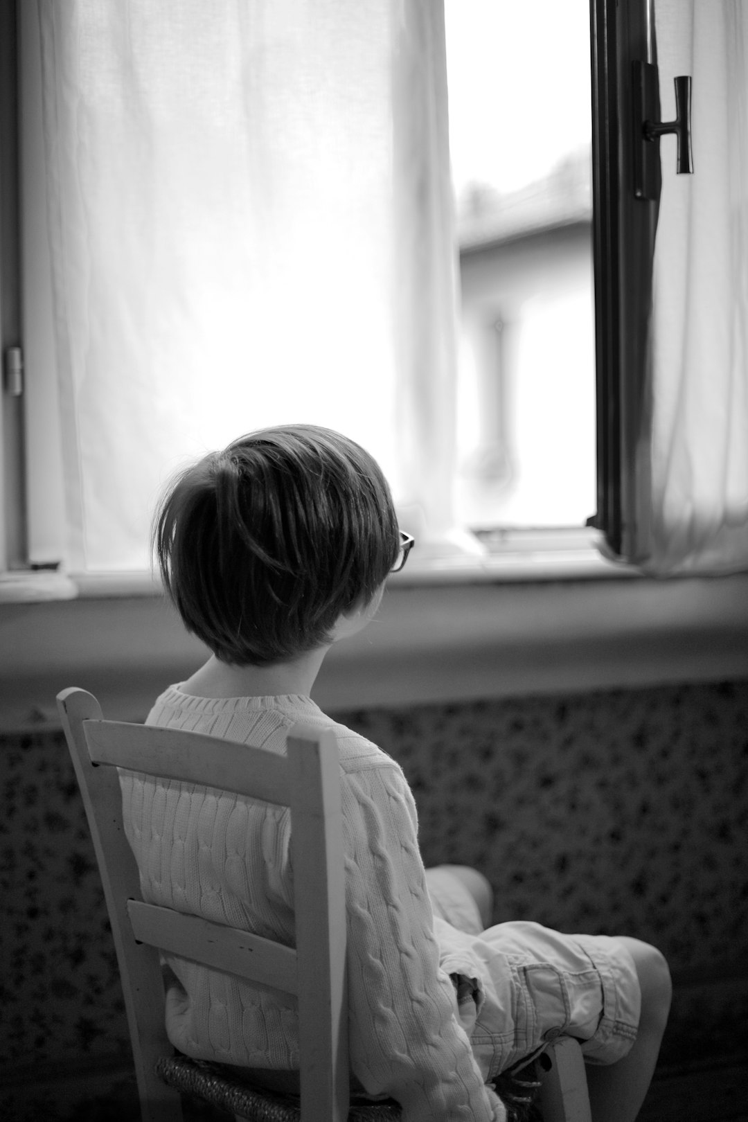 grayscale photo of child sitting on chair