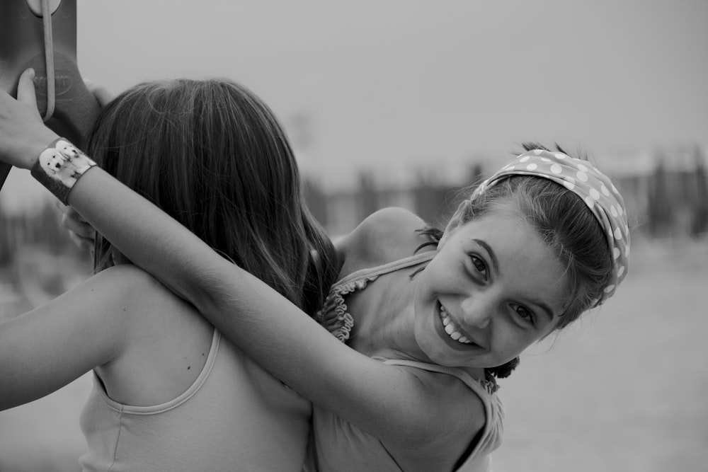 two young girls hugging each other on a beach