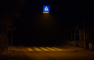 A stylish pedestrian crossing sign illuminated by soft evening light on a quiet city street.