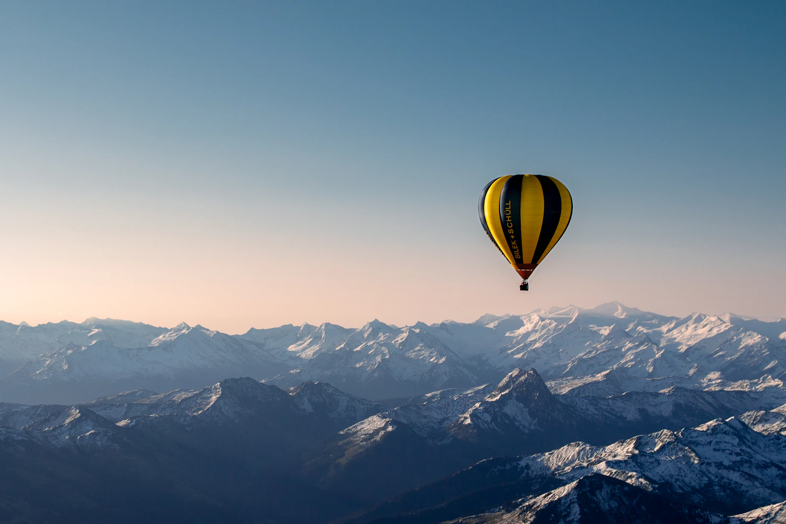 Воздушный шар летит над горным хребтом — Airballoon.uz