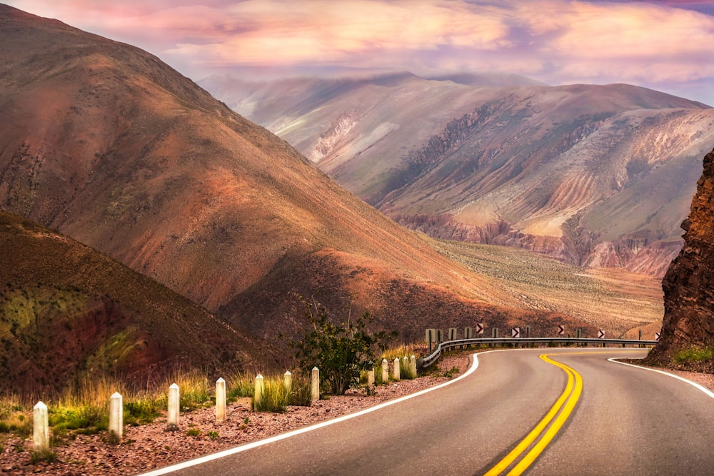 gray concrete road near brown mountains during daytime