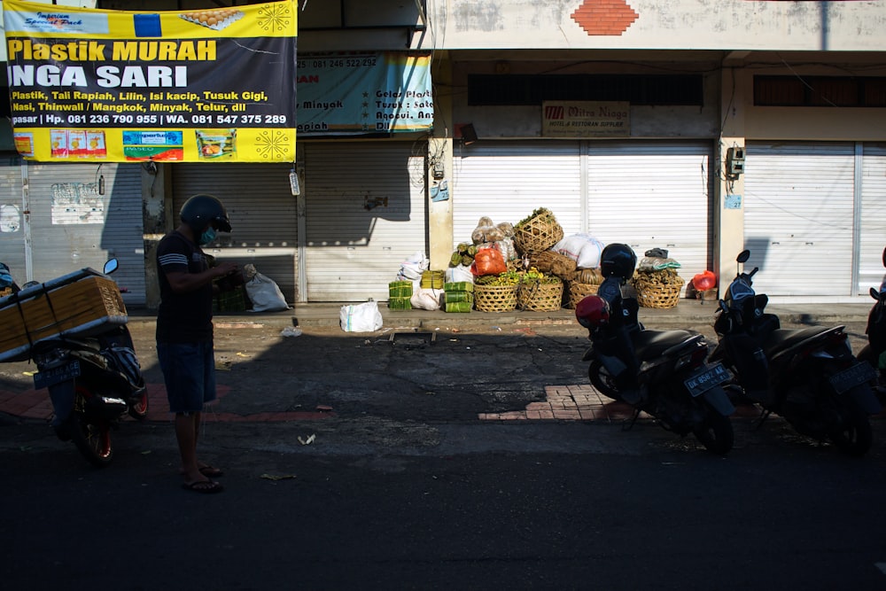 man in black jacket standing near black motorcycle during daytime