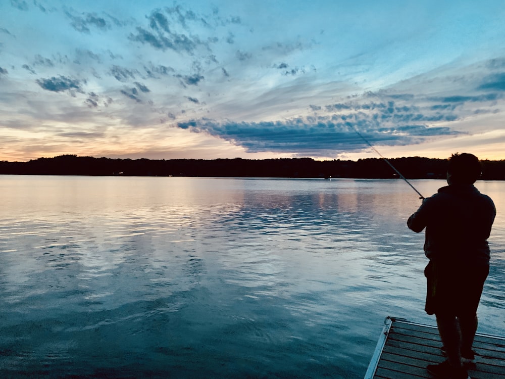 person fishing on sea during sunset