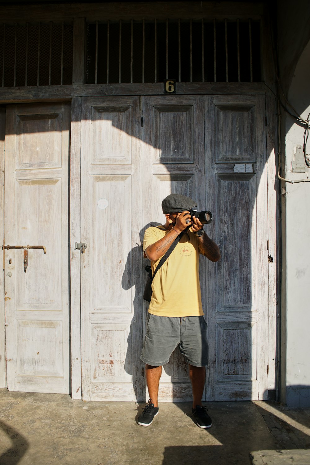 man in yellow t-shirt and blue denim shorts standing beside white wooden door