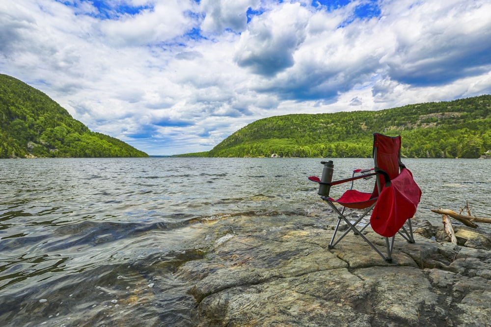red and black camping chair on river during daytime