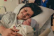 A joyful new mother holding her newborn wrapped in a soft blanket, smiling with gratitude.