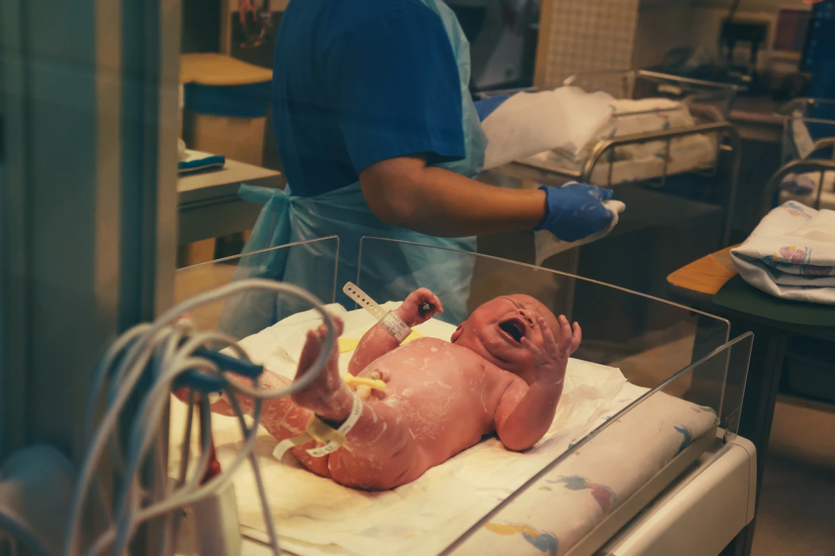 Clinician in blue scrubs gently holding a newborn baby