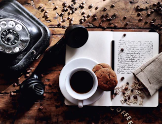 white ceramic mug on white ceramic saucer beside black dslr camera