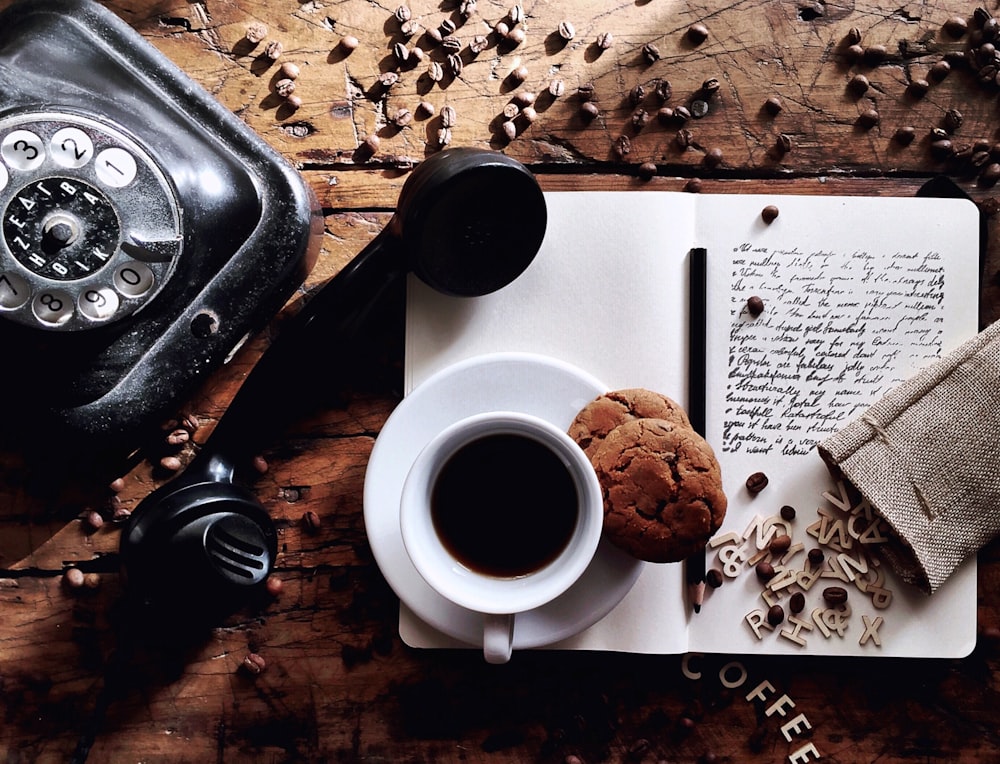 white ceramic mug on white ceramic saucer beside black dslr camera