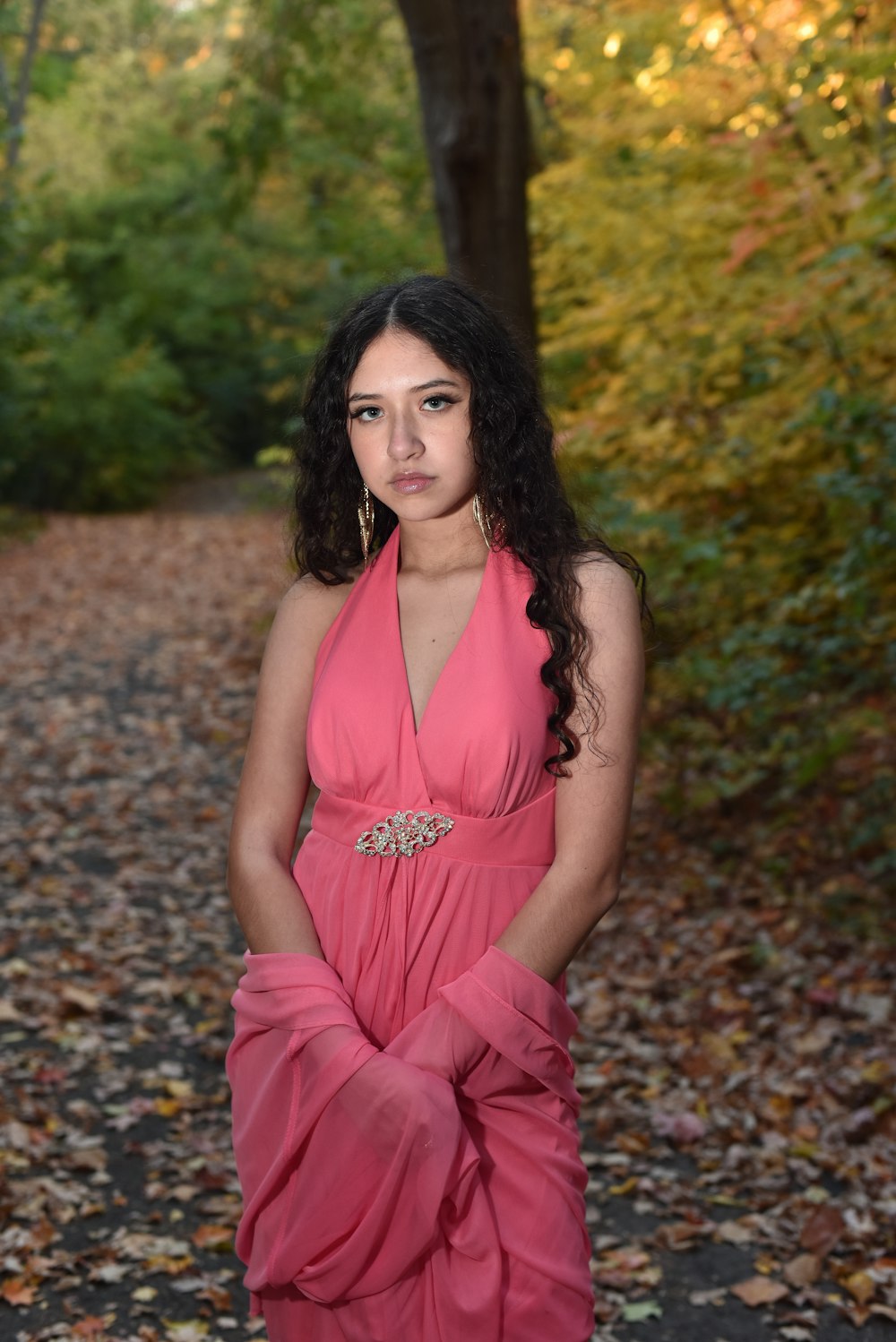 woman in pink spaghetti strap dress sitting on brown dried leaves during daytime