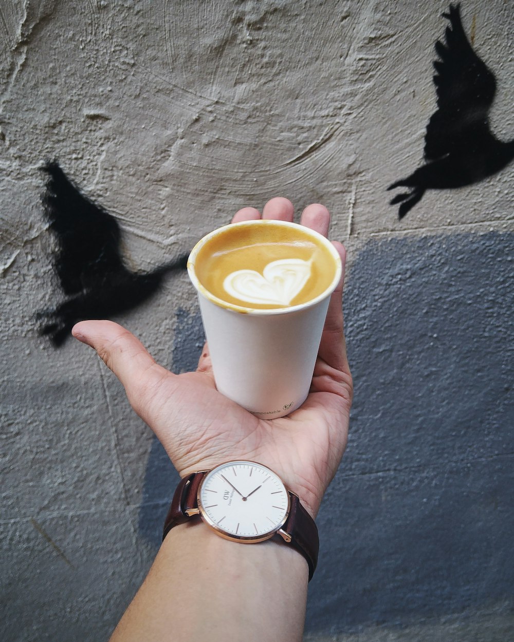 person holding white plastic cup with yellow liquid