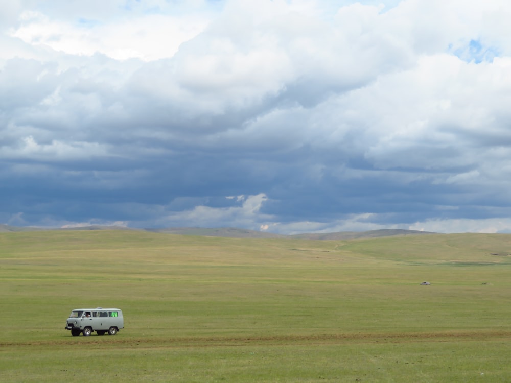 white van on green grass field under white clouds during daytime