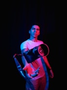 man in pink t-shirt holding black and green headphones