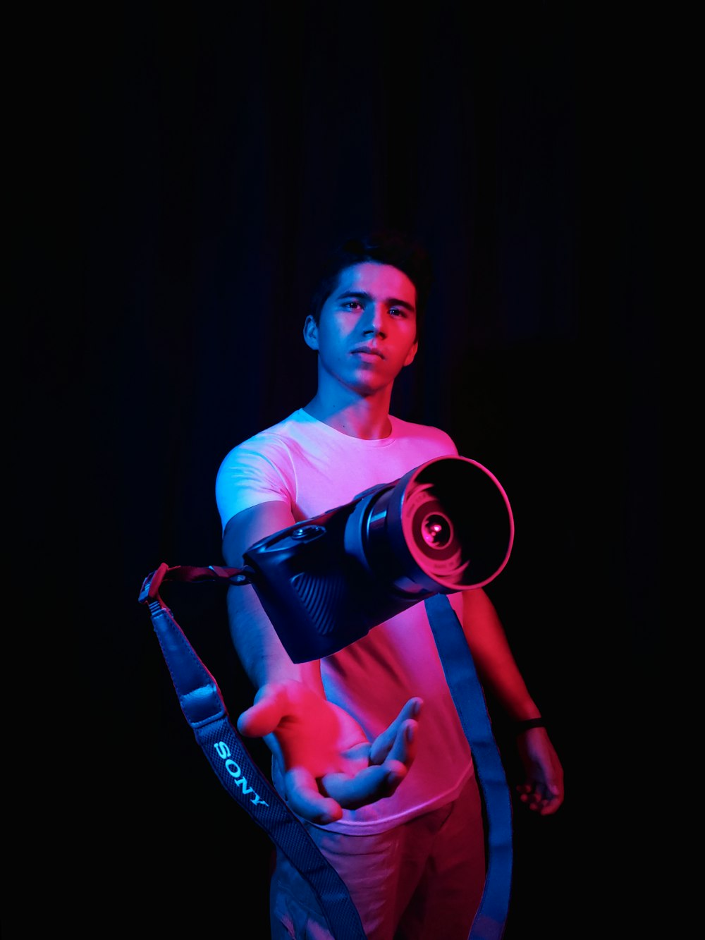 man in pink t-shirt holding black and green headphones