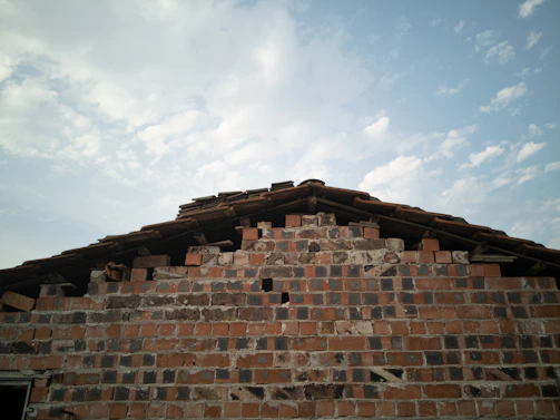 A friendly mason working on a brick wall under a clear sky.