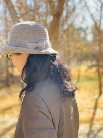 A wool cloche hat with a subtle bow detail, photographed against a backdrop of autumn leaves.