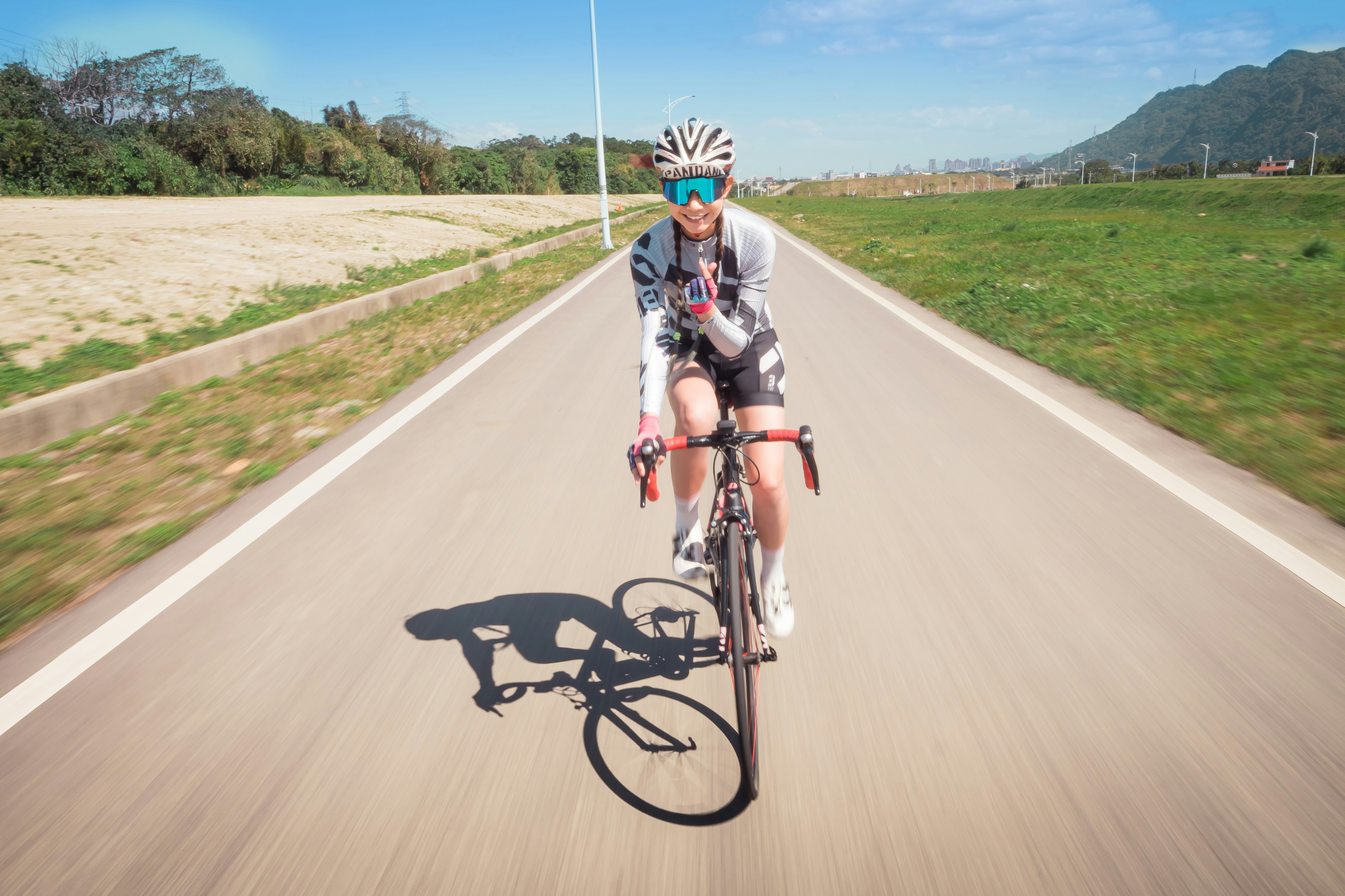 man in black and white shirt riding on bicycle on road during daytime