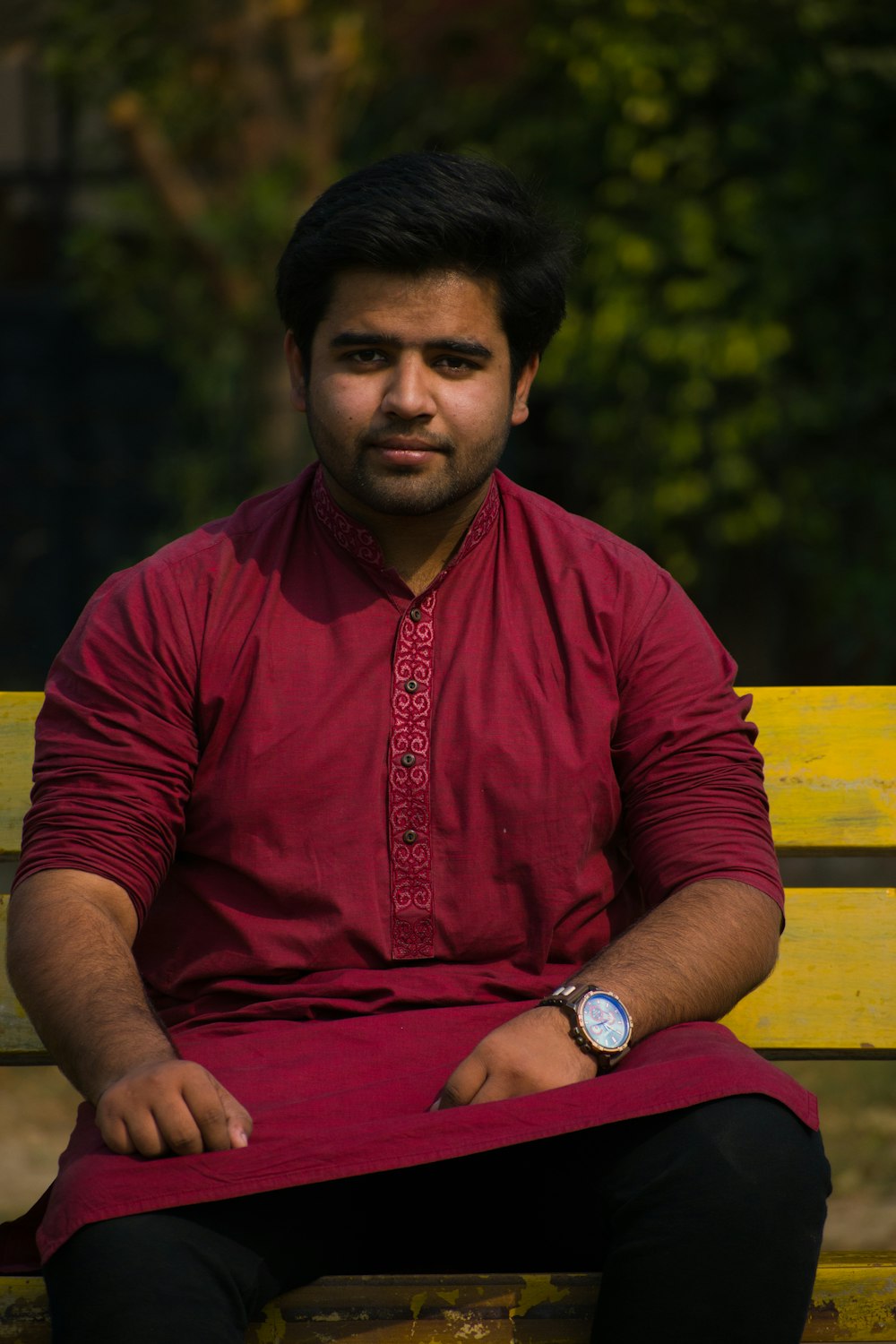 man in red crew neck t-shirt sitting on yellow wooden bench