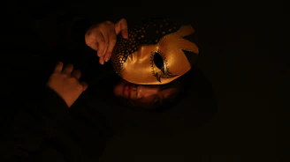 Close-up of a sleek black mask with gold accents resting on dark velvet.