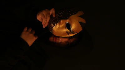 Close-up of a sleek black mask with gold accents resting on dark velvet.