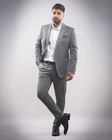 A groom wearing a tailored jodhpuri suit standing confidently against a minimalist backdrop.