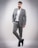 A stylish man in a tailored suit standing confidently against a minimalist urban backdrop.