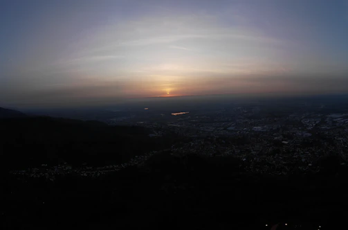 A panoramic shot of the city skyline at sunset, with soft pink and orange hues.