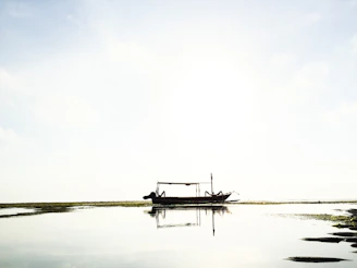 A serene image of a small boat effortlessly floating on calm waters at sunrise, symbolizing resilience and steady progress.