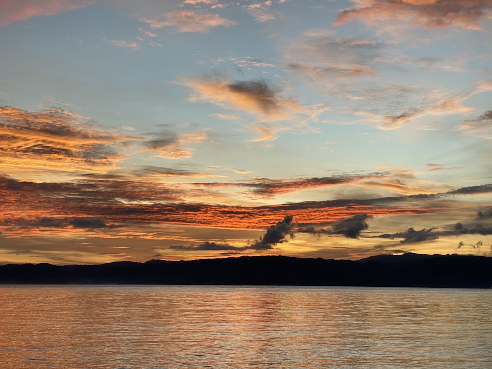 body of water under cloudy sky during sunset