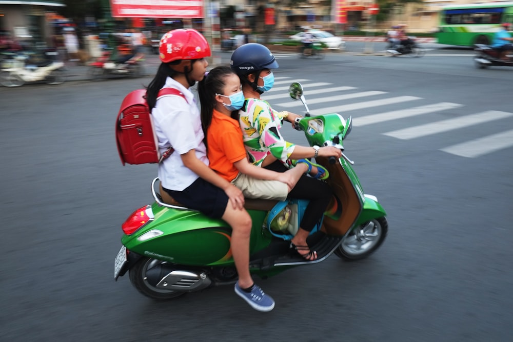 man in white shirt and red helmet riding green motor scooter on road during daytime