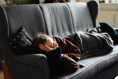 woman in pink jacket lying on gray couch lazy teams background