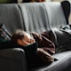 woman in pink jacket lying on gray couch