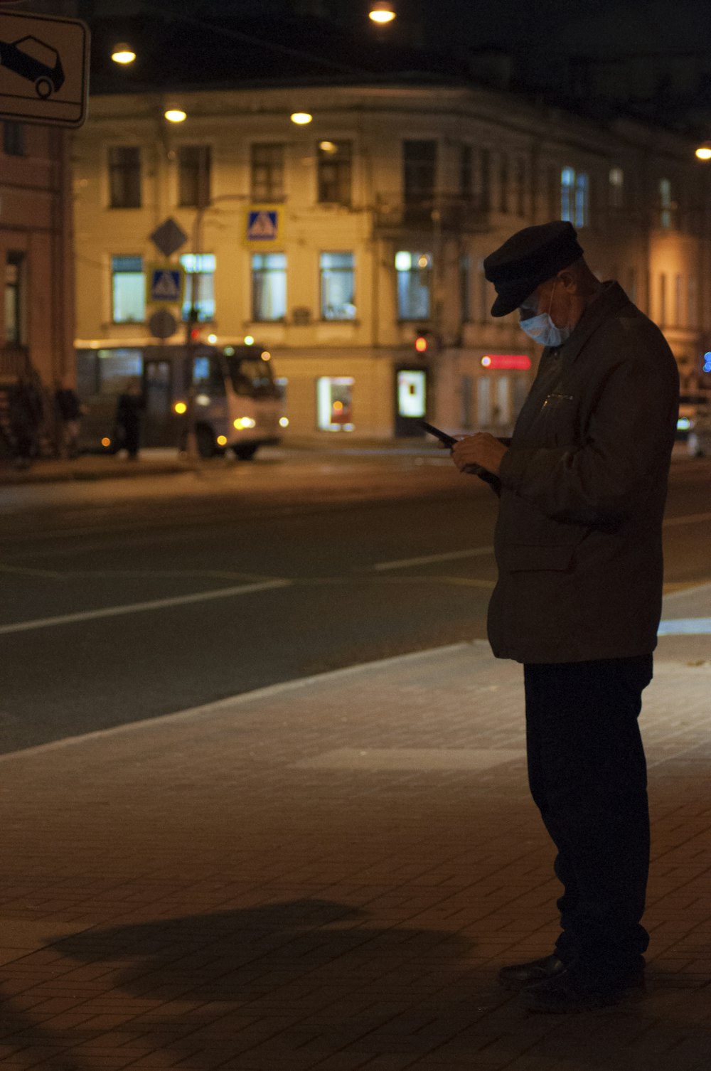 man in black coat standing on sidewalk during night time