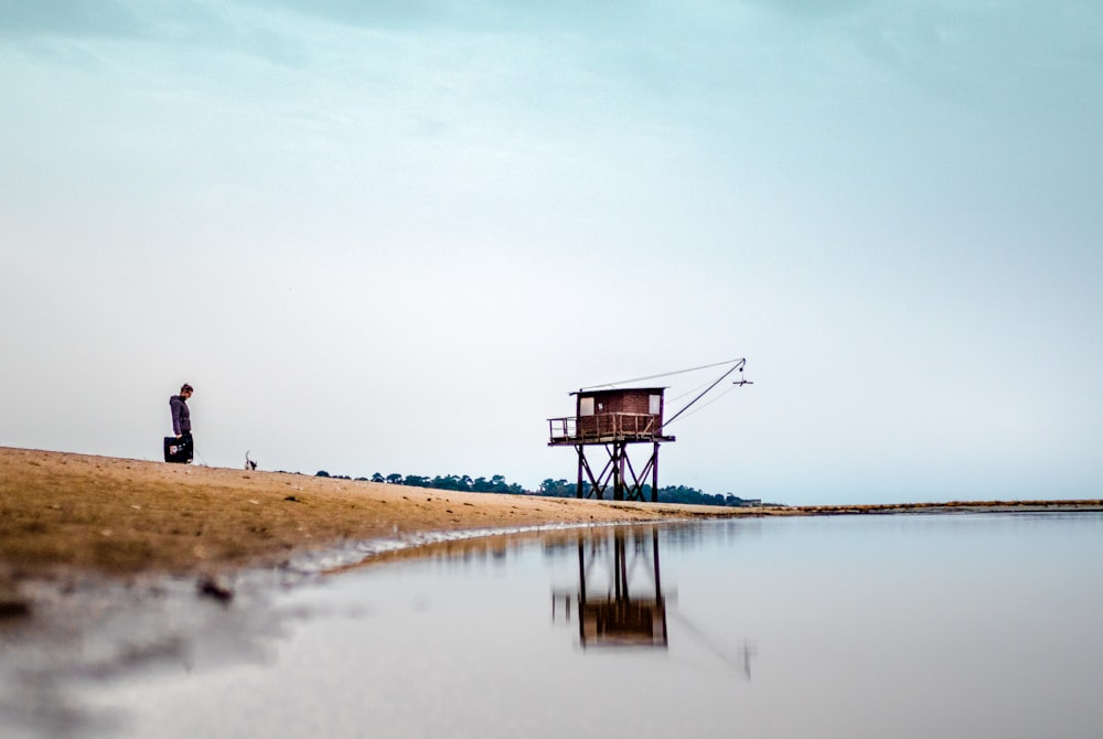 brown wooden house on brown sand near body of water during daytime