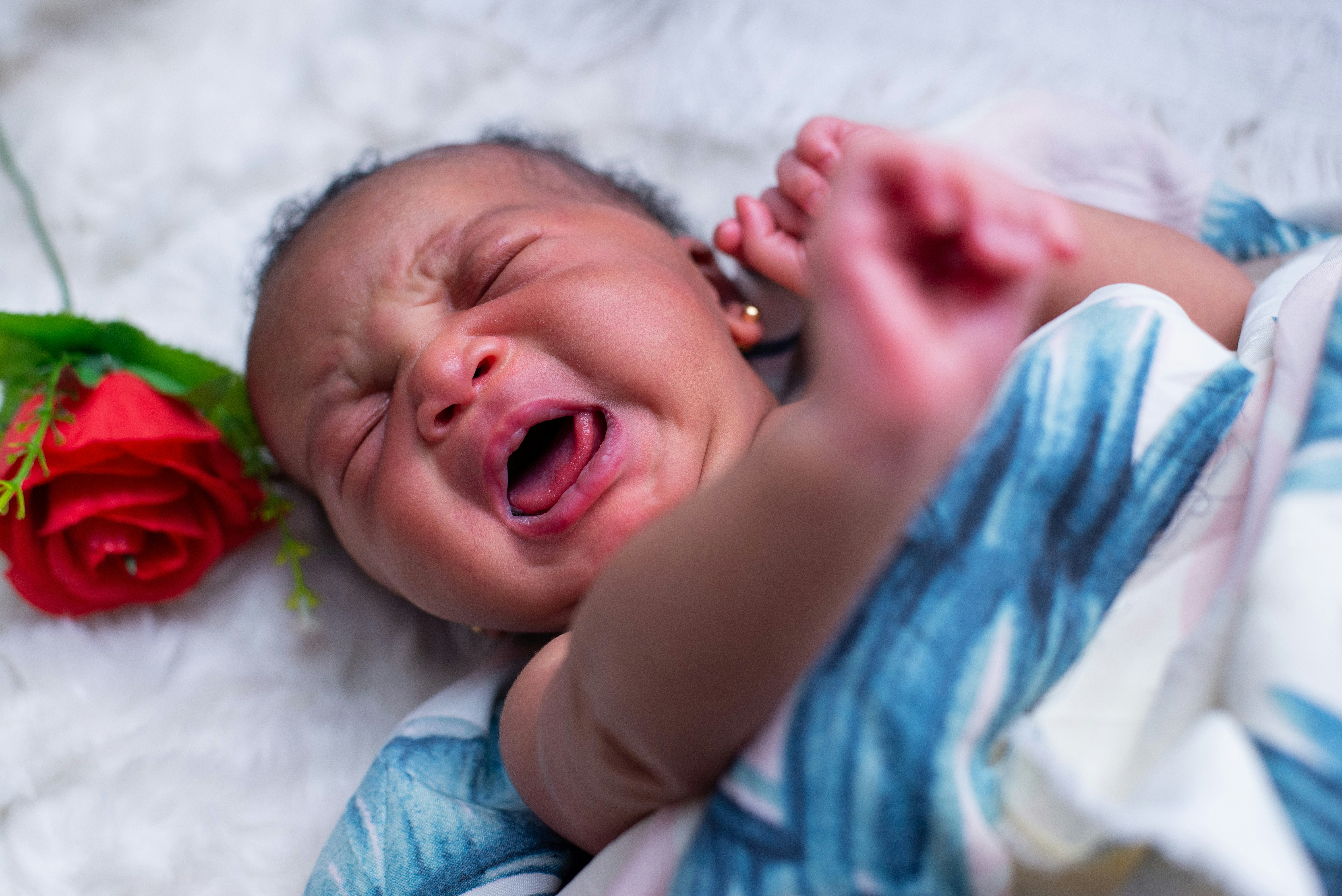 baby in blue shirt lying on white textile