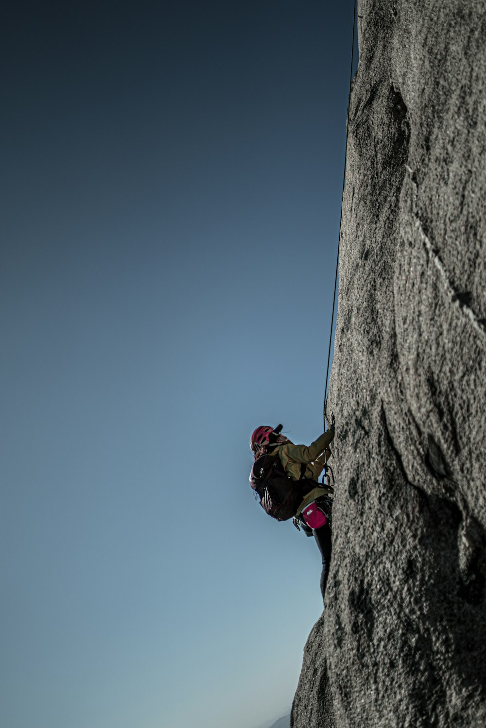 man in red jacket climbing on mountain during daytime