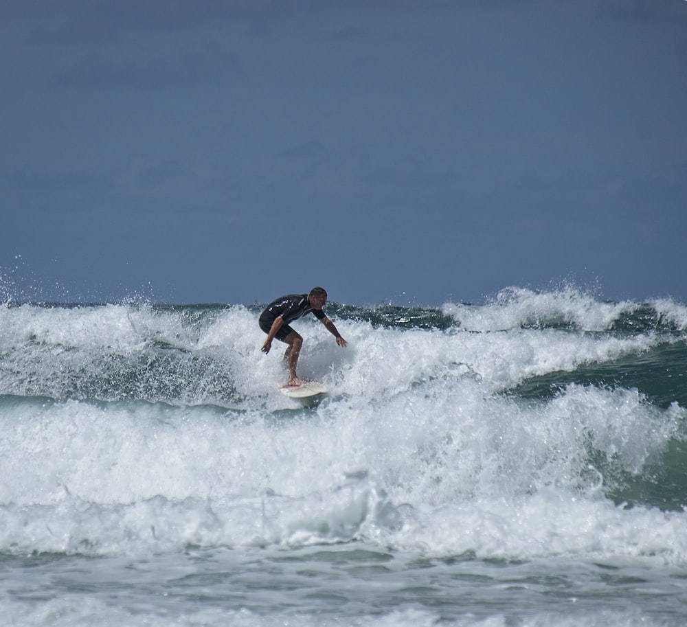 man in red shorts surfing on sea waves during daytime