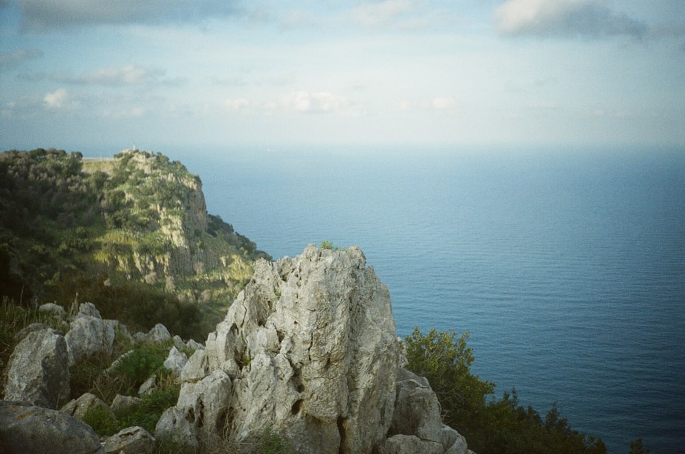 gray rocky mountain beside blue sea under white sky during daytime