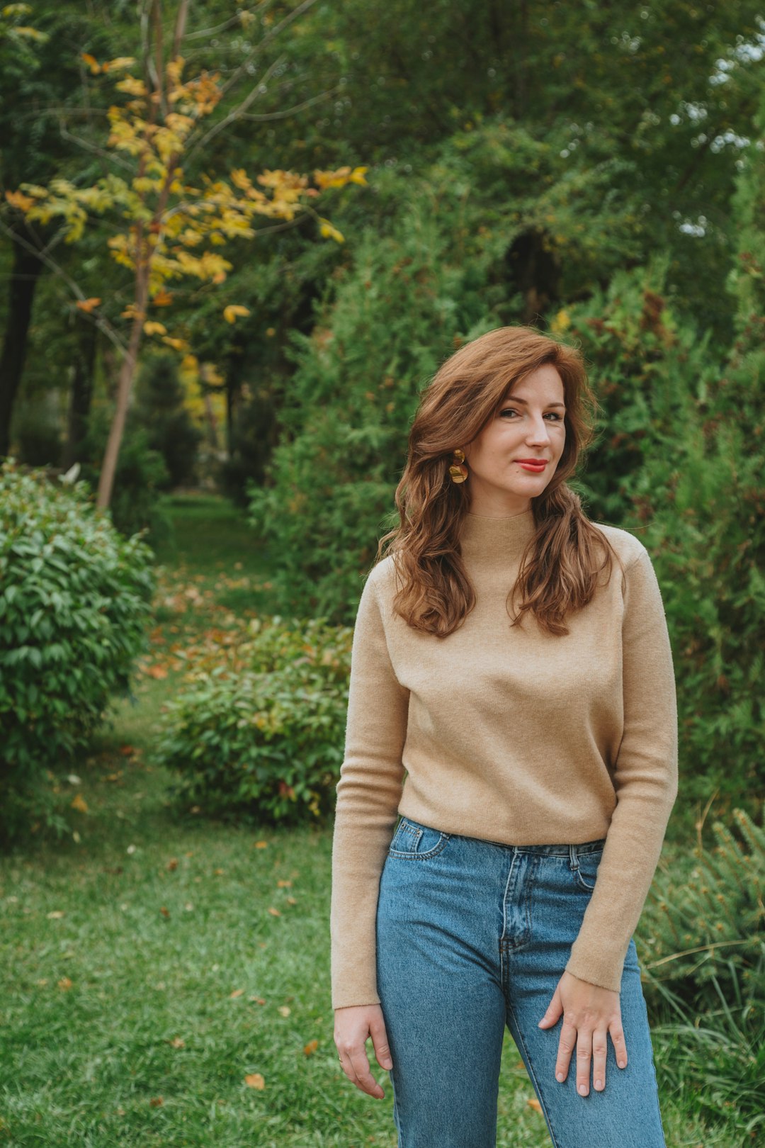 woman in beige long sleeve shirt and blue denim jeans standing near green plants during daytime