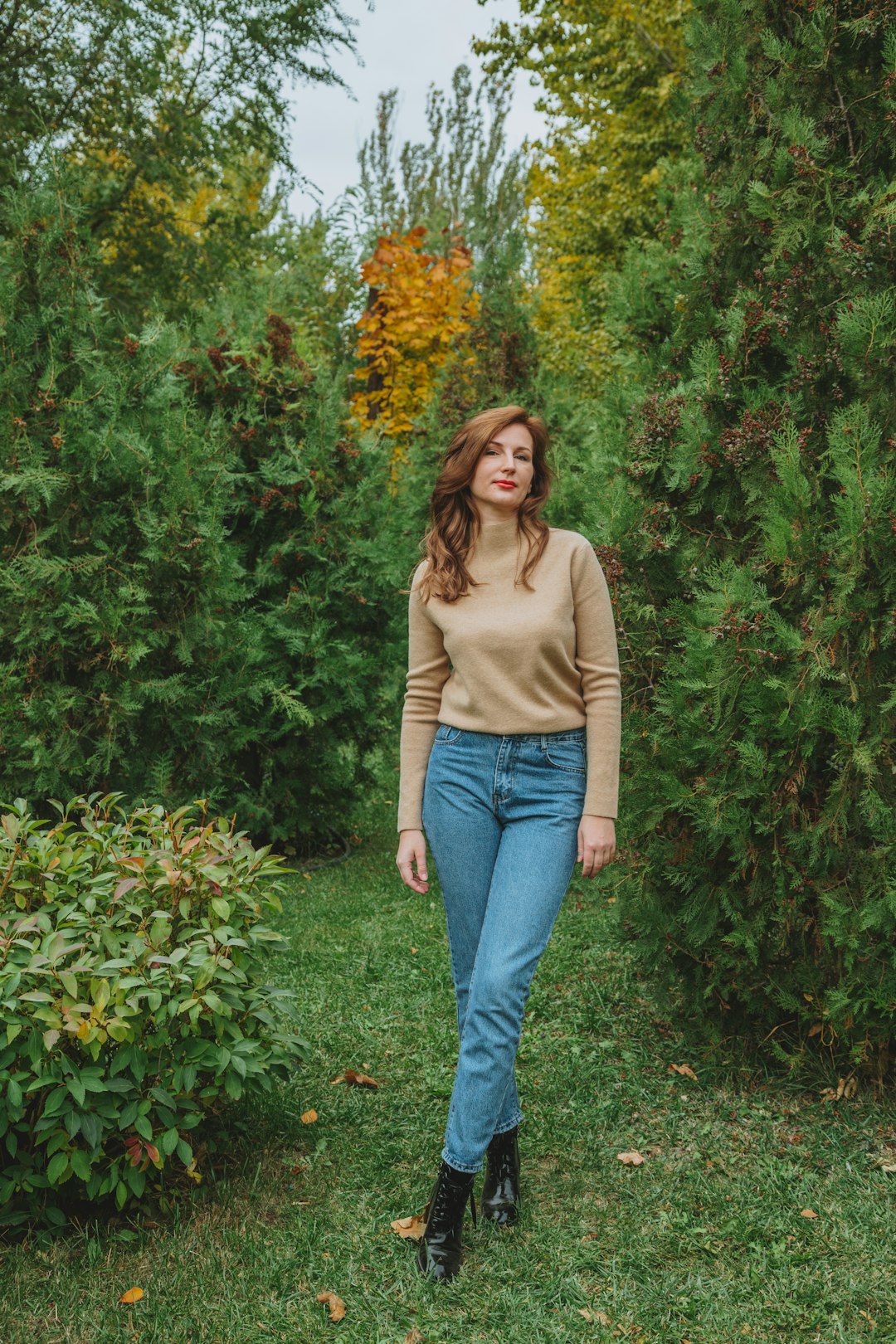 woman in brown long sleeve shirt and blue denim jeans standing near green plants