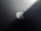 A minimalist design featuring a metallic surface with a prominent logo shaped like an apple with a bite taken out of it. The lighting creates a gradient effect, adding a sleek and modern aesthetic.