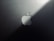 A minimalist design featuring a metallic surface with a prominent logo shaped like an apple with a bite taken out of it. The lighting creates a gradient effect, adding a sleek and modern aesthetic.