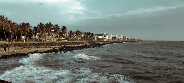 A calm Hawaiian coastline with a cozy island home nestled among palm trees at sunset.
