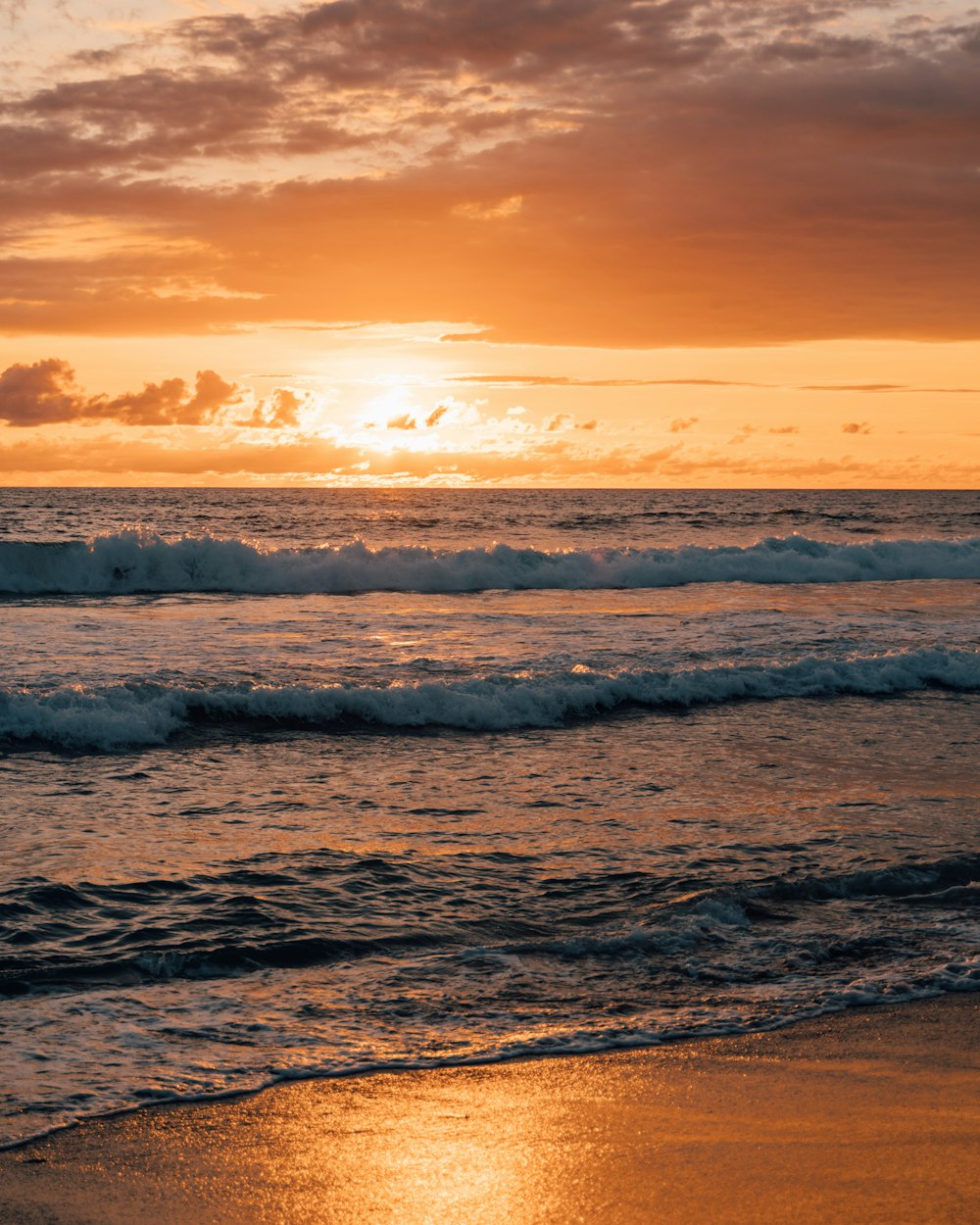 ocean waves crashing on shore during sunset