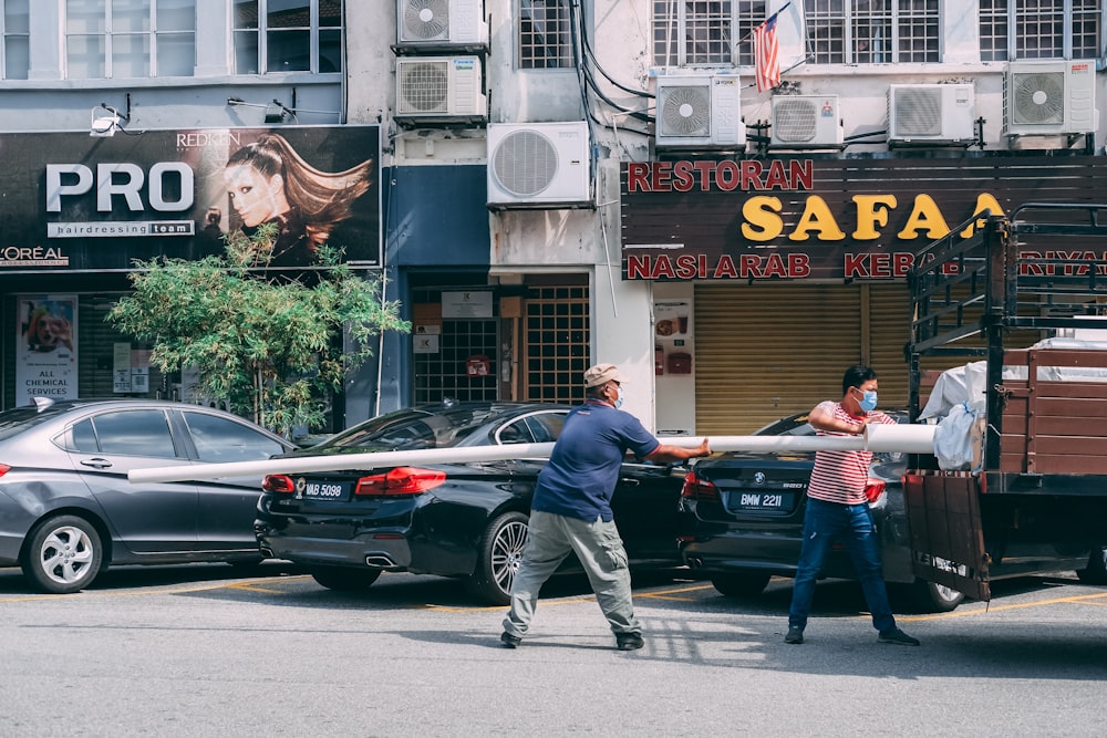 homem em jaqueta preta e jeans azul de pé ao lado de sedan preto durante o dia