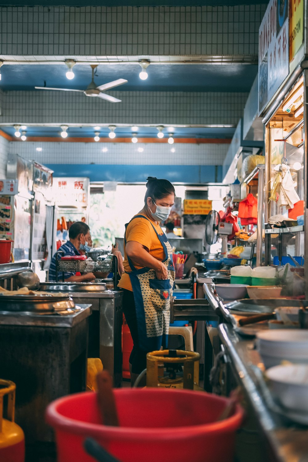 man in orange polo shirt standing in front of food stall