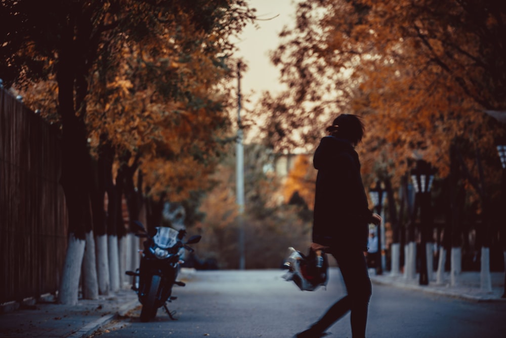 man in black jacket and pants walking on sidewalk during daytime